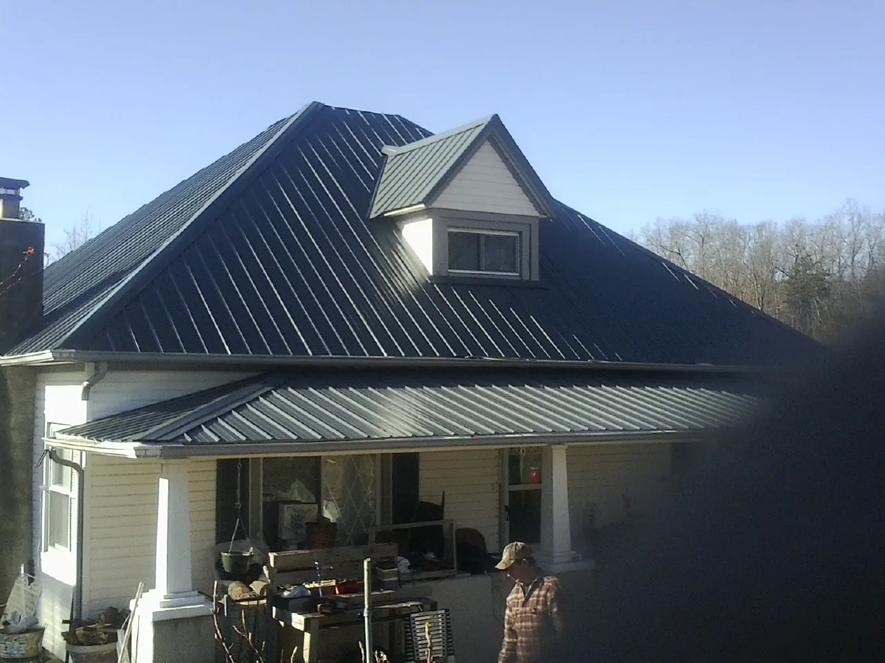 Dark blue standing seam metal roof with a dormer above a front porch in Middleport