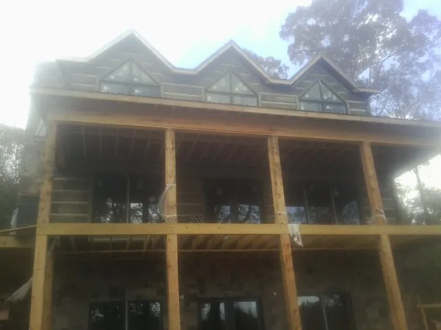 Dormers and porch framing on a large log home under construction — Roof Coating work by our crew in Middleport